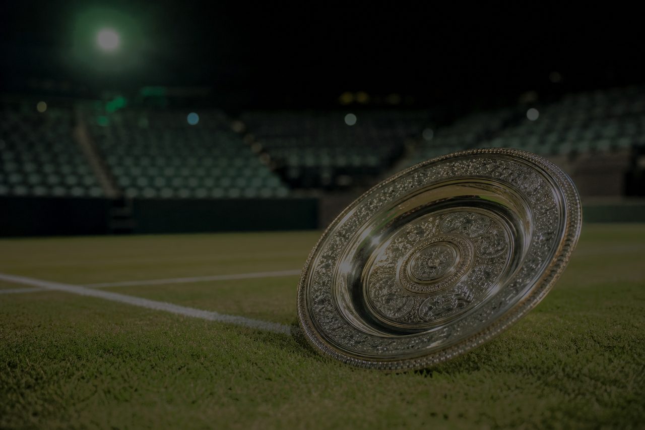 Silberne Siegerschale auf geschnittenem Rasen neben einem Tennisplatz